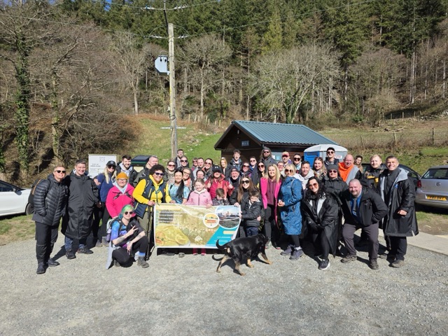 A large Nature Awareness group posed with a banner at the start of a spring walk.