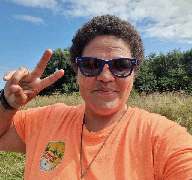 Leah Fitzpatrick outdoors in a meadow, in a Nature Awareness t-shirt.